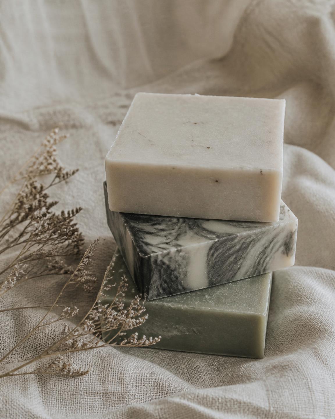 Stack of handmade cold-process soap bars resting on natural linen